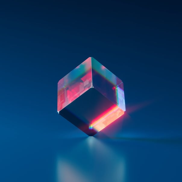 a dark blue cube reflecting red light standing on one of the edges